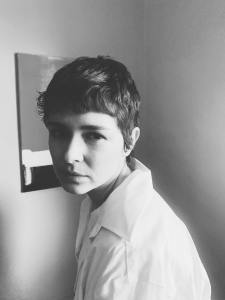 a black and white, three-quarter-turn portrait of a caucasian woman with short, cropped hair, wearing a white, collared dress shirt.